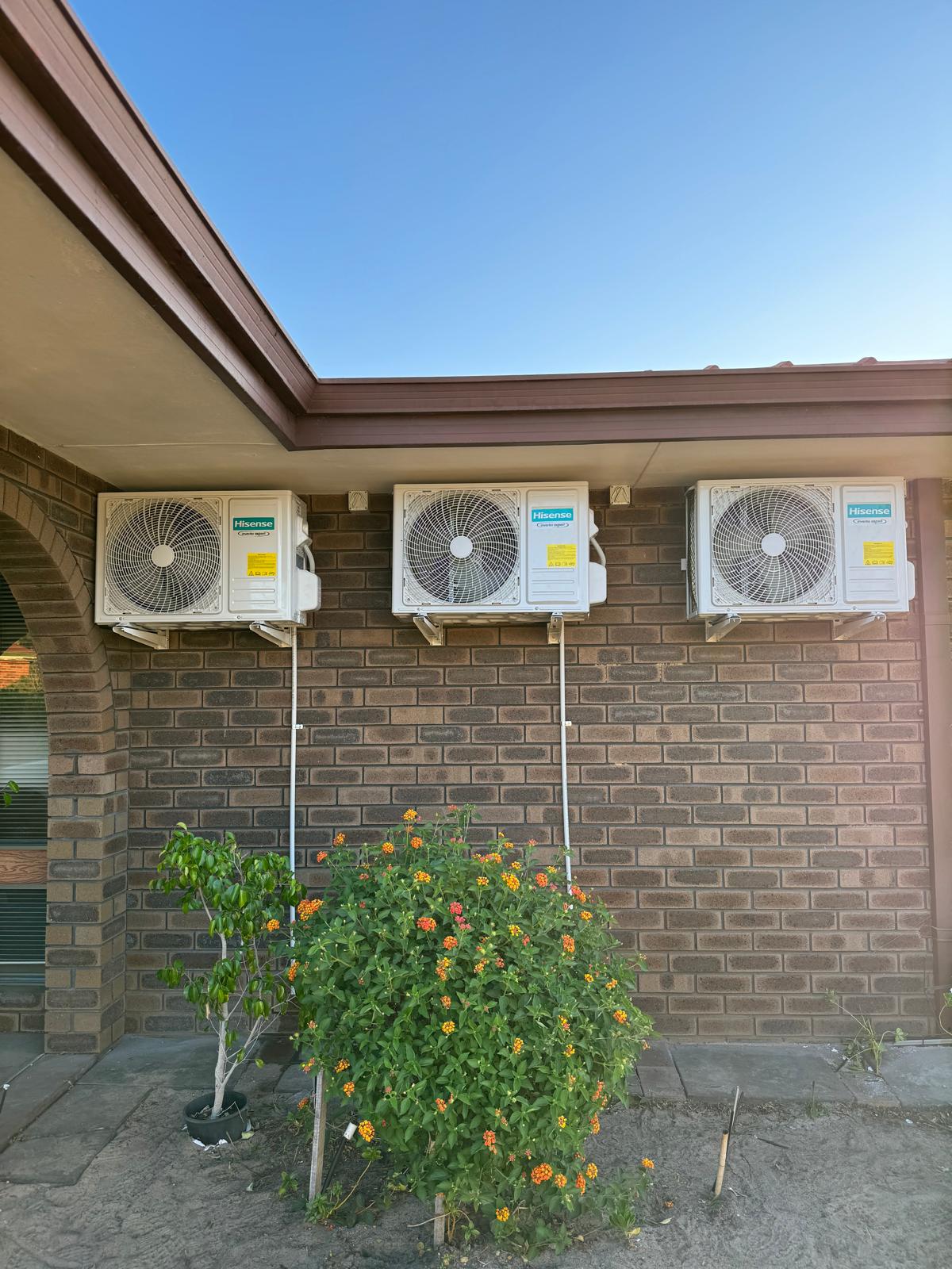 Three Hisense split system outdoor units lined up on a Perth brick home